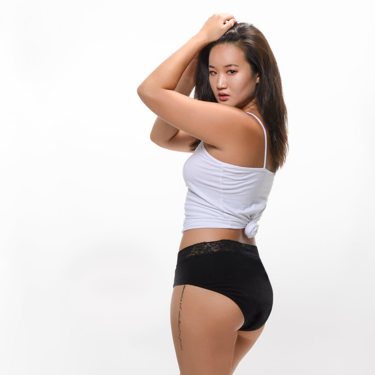 Woman modeling black period underwear with lace waistband on white background