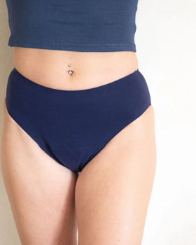Woman wearing high-waisted navy blue period underwear on light background