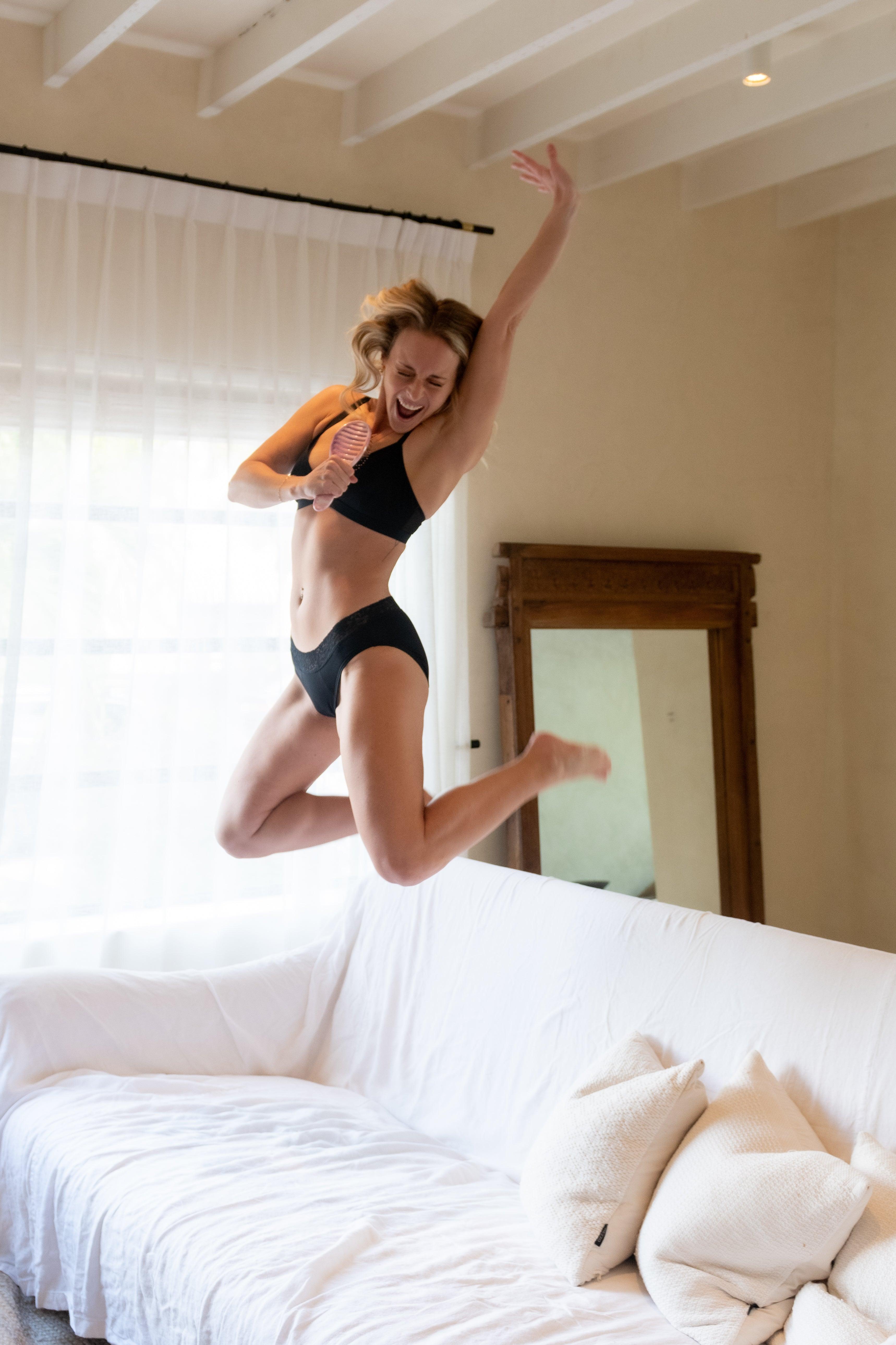 Woman jumping on a couch with Heralogie period underwear